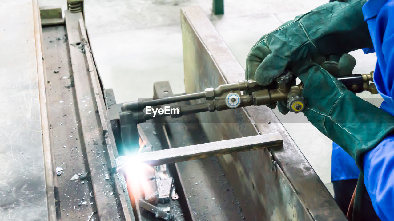Midsection of welder welding metal in workshop