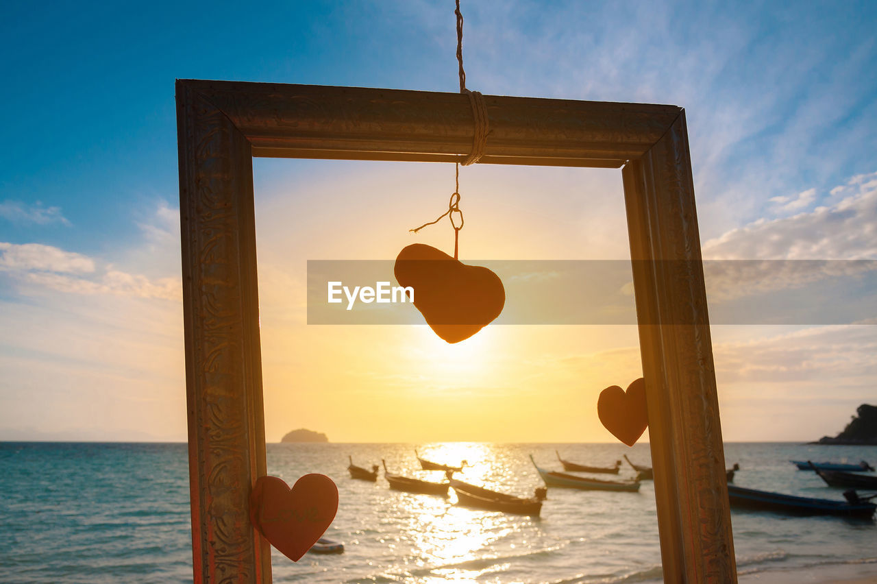 CLOSE-UP OF HEART SHAPE HANGING OVER SEA AGAINST SKY