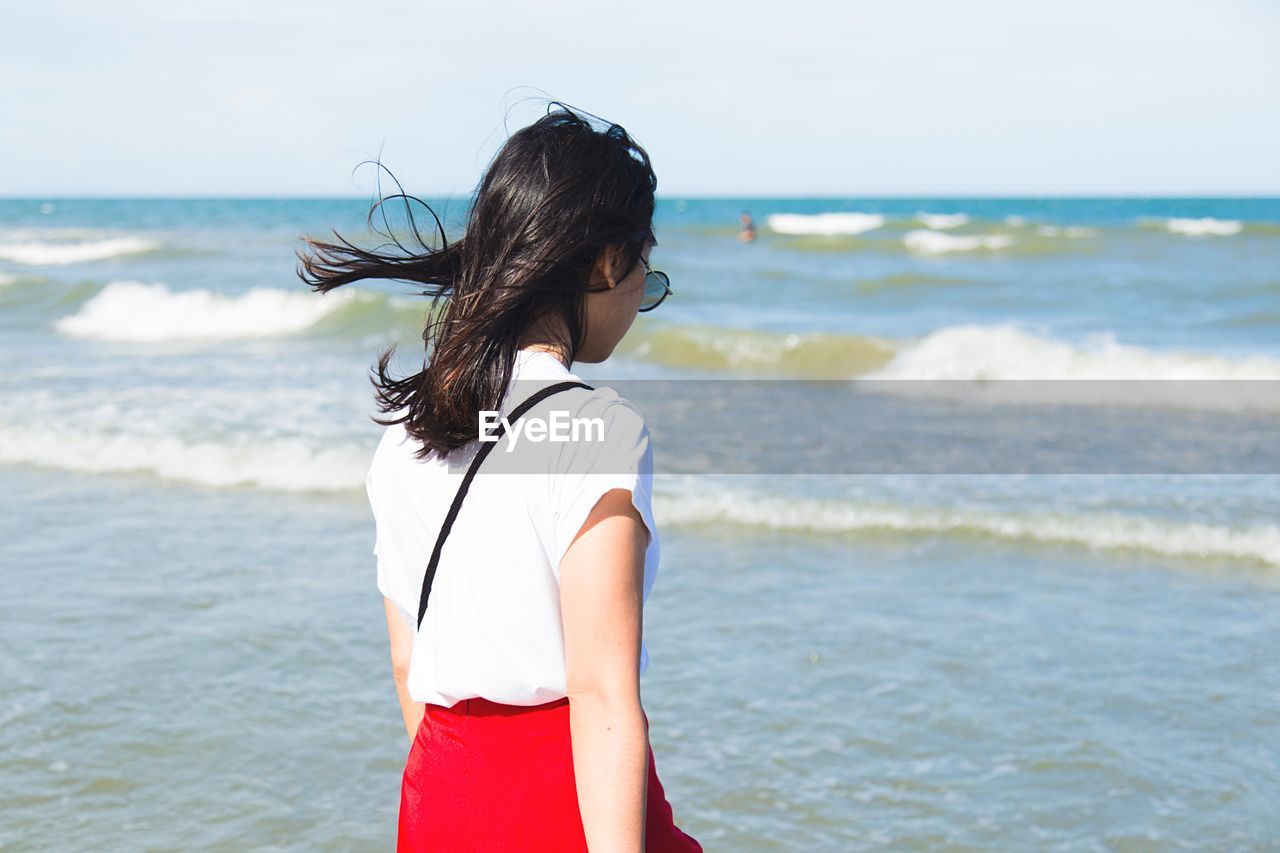 Woman standing at beach against sky