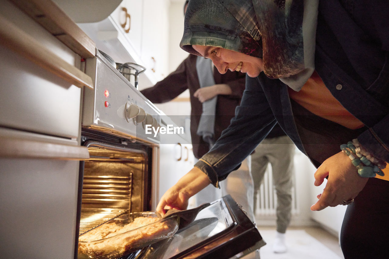 Woman taking food for eid al-fitr out of oven