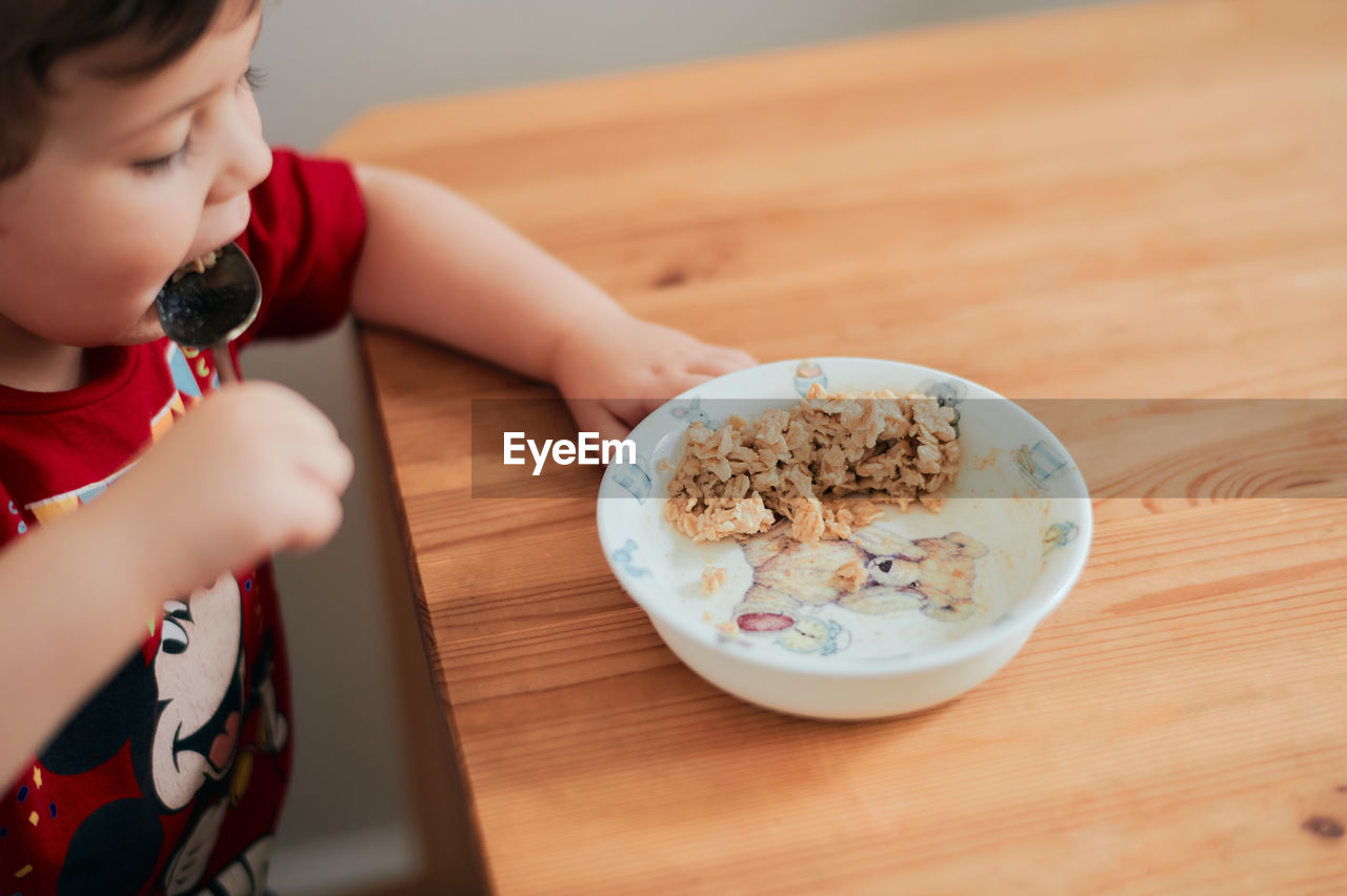 A boy is eating oatmeal for breakfast at the kitchen table