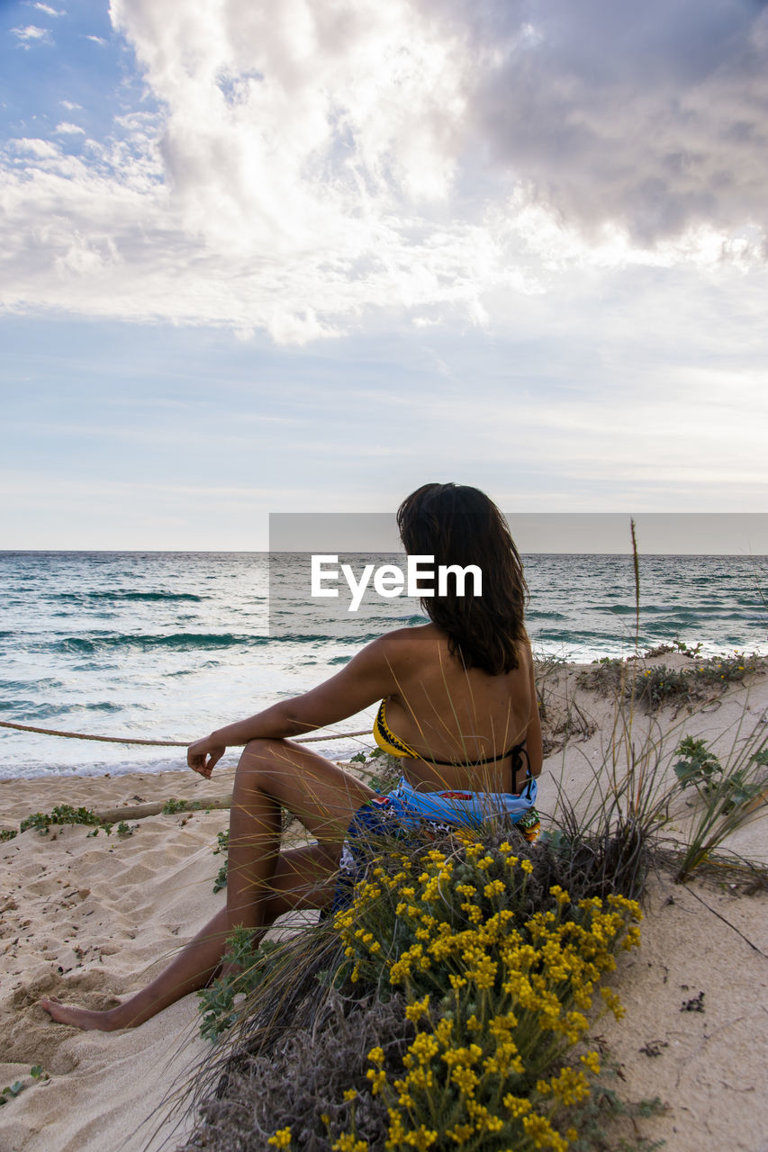 Rear view of woman sitting on beach