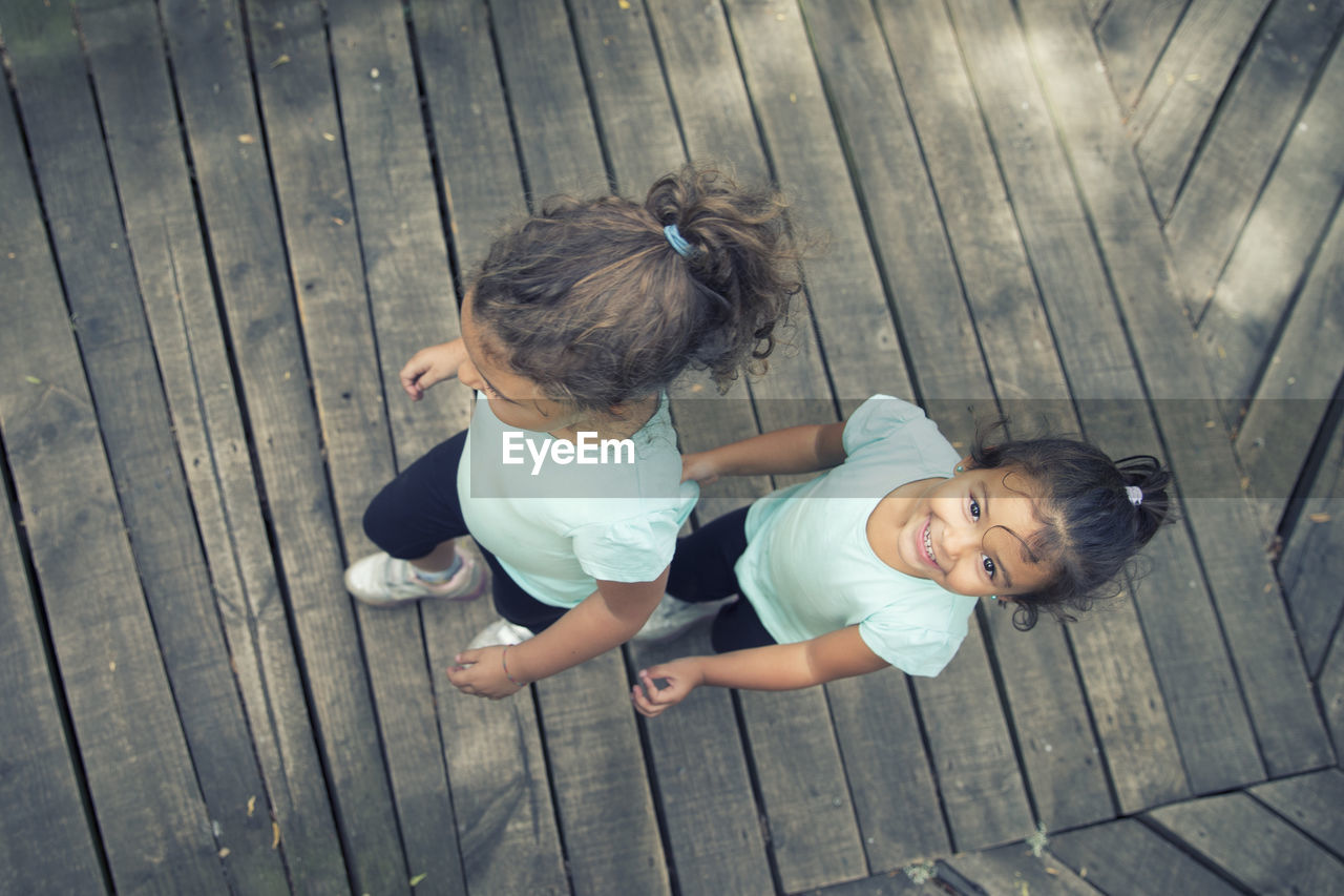 HIGH ANGLE VIEW OF CUTE BABY GIRL ON WOODEN FLOOR