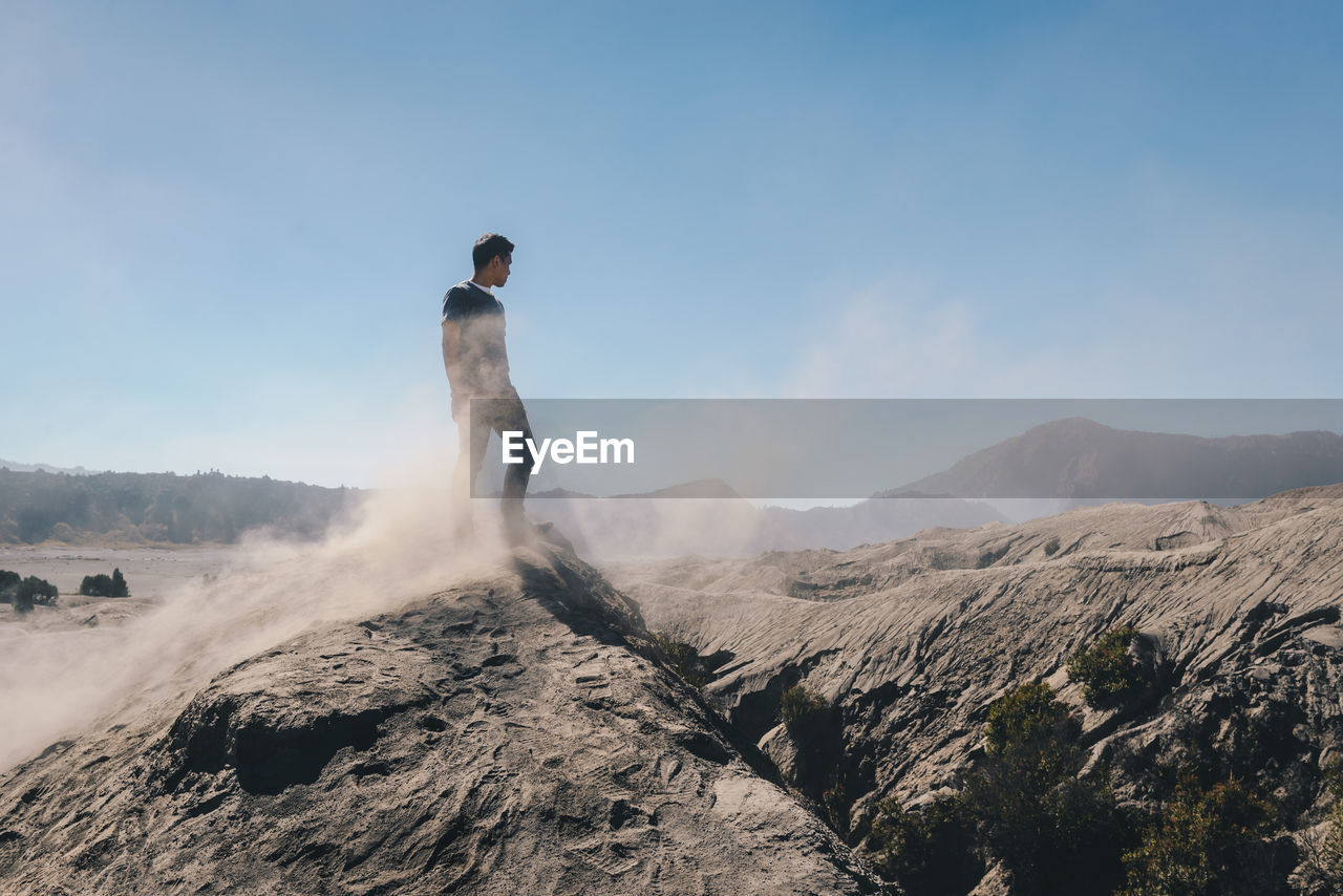 Man standing on rock against clear blue sky