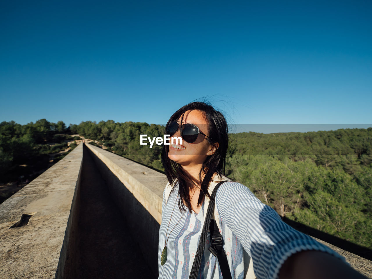 Portrait of smiling woman against clear blue sky