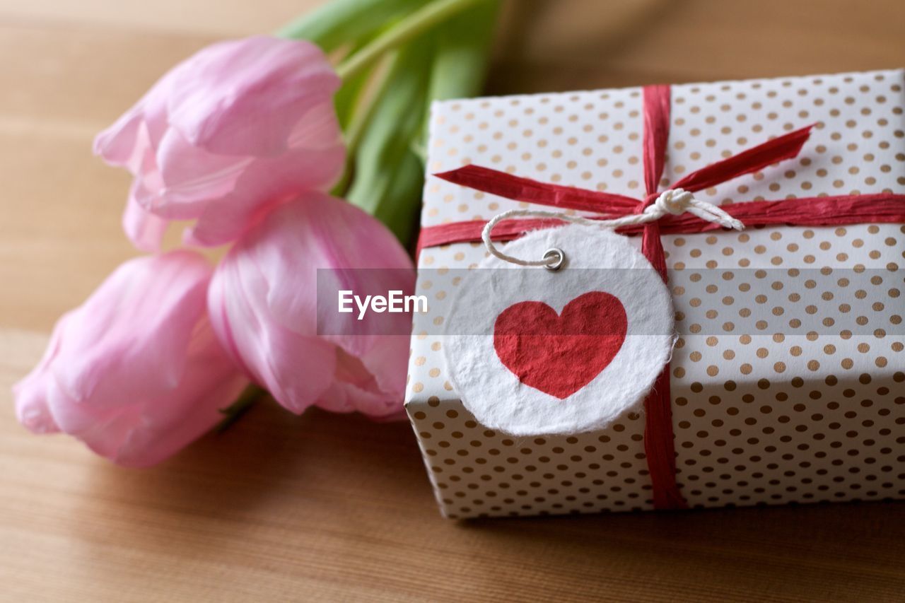 Close-up of gift with tulips on table