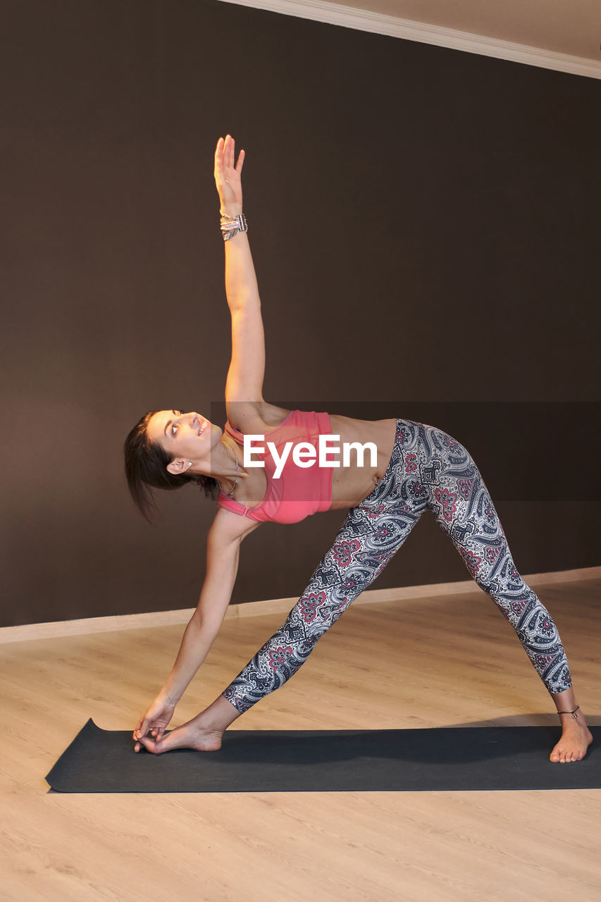 Young woman doing yoga on yoga mat in atmospheric yoga studio