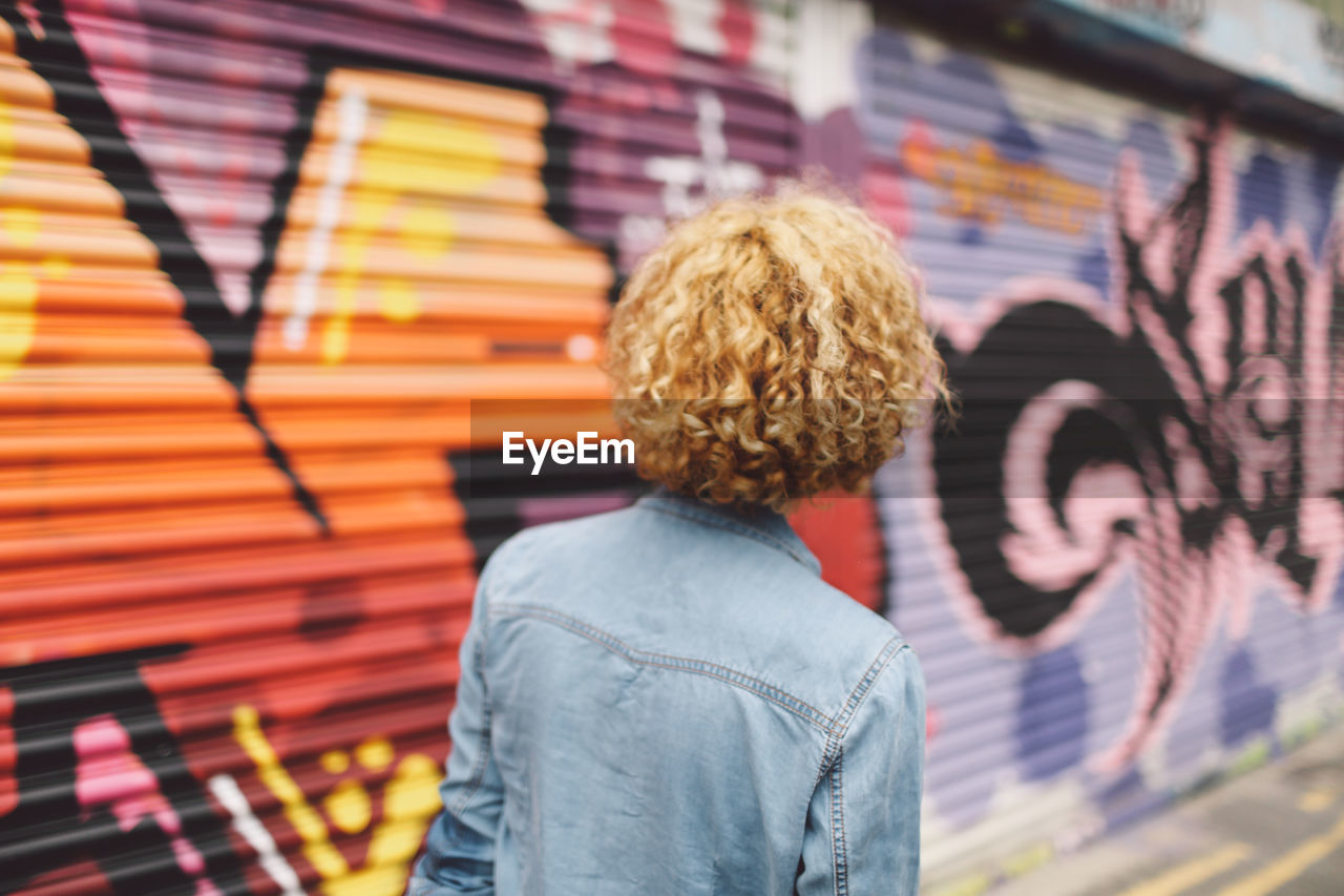 Young woman standing against graffiti shutter