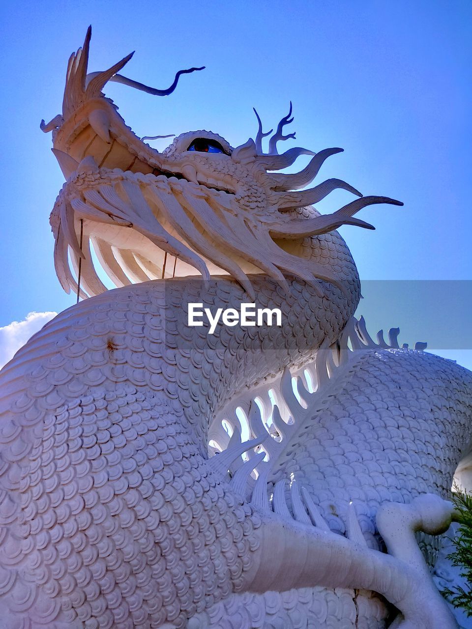 Low angle view of statue against blue sky and building