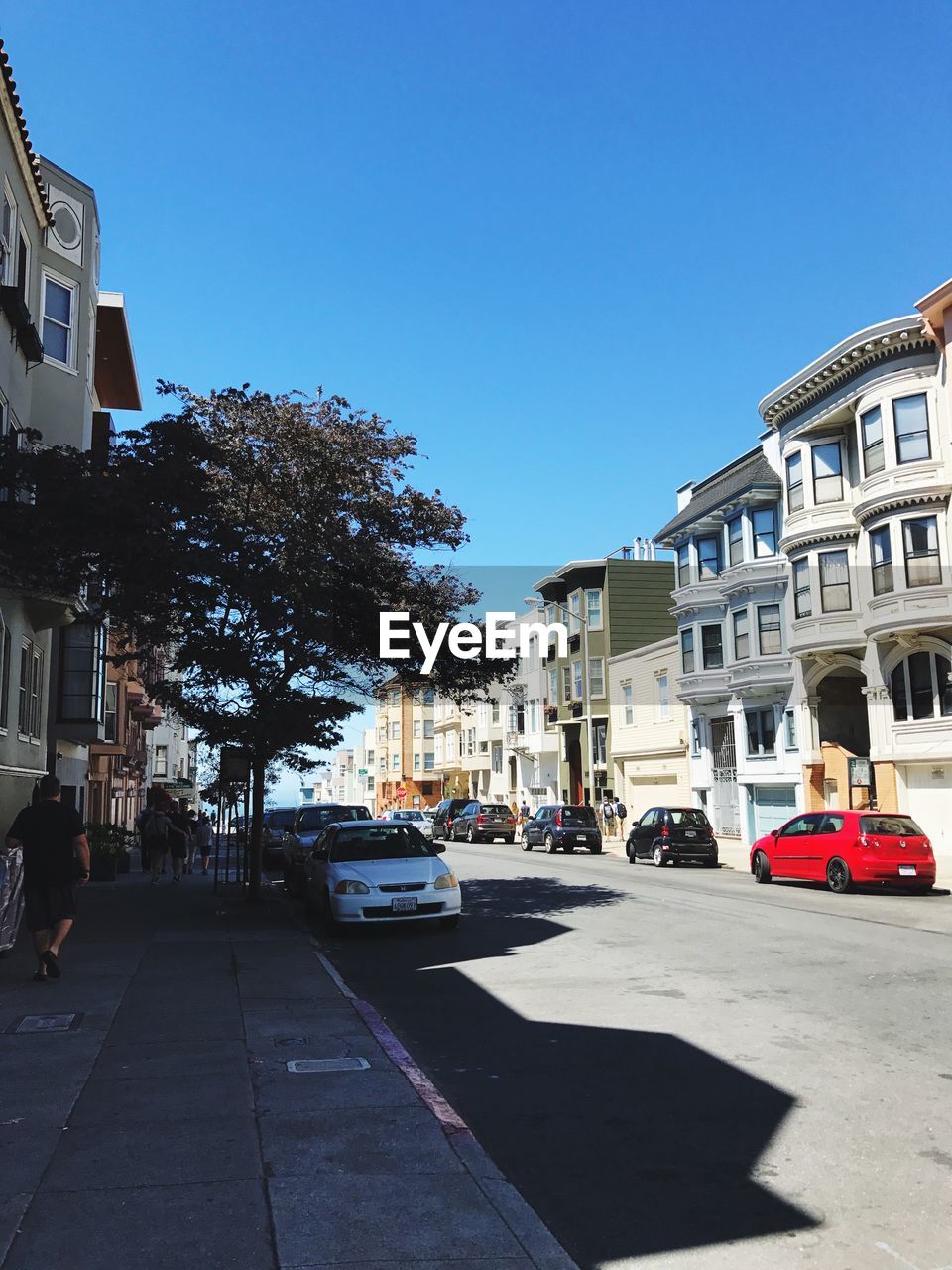 CARS ON ROAD BY BUILDINGS AGAINST CLEAR SKY