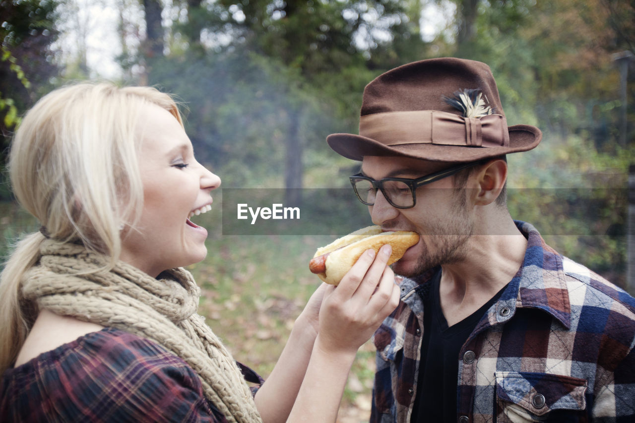 Woman feeding man while standing at backyard