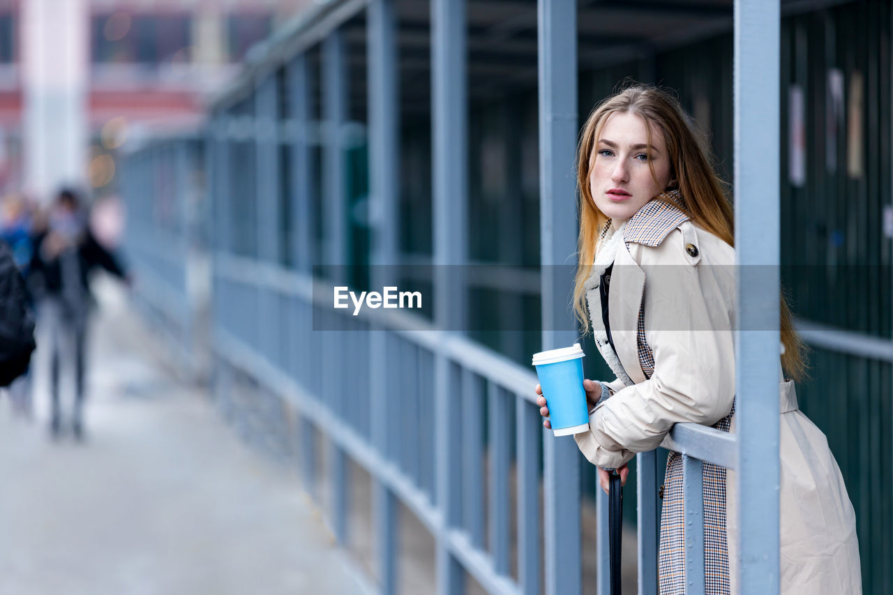 Young stylish woman drinking coffee in a city street.