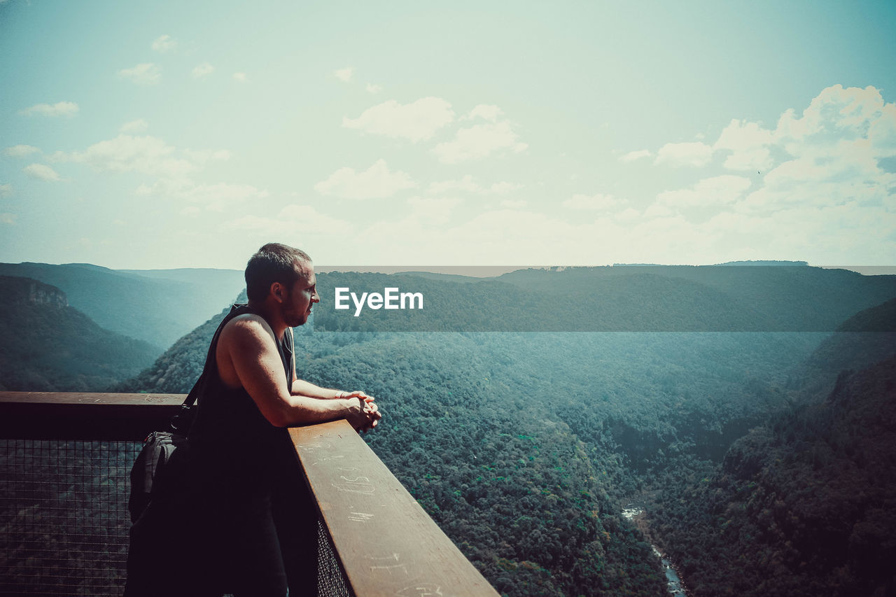 Side view of young man looking at mountains on a landscape