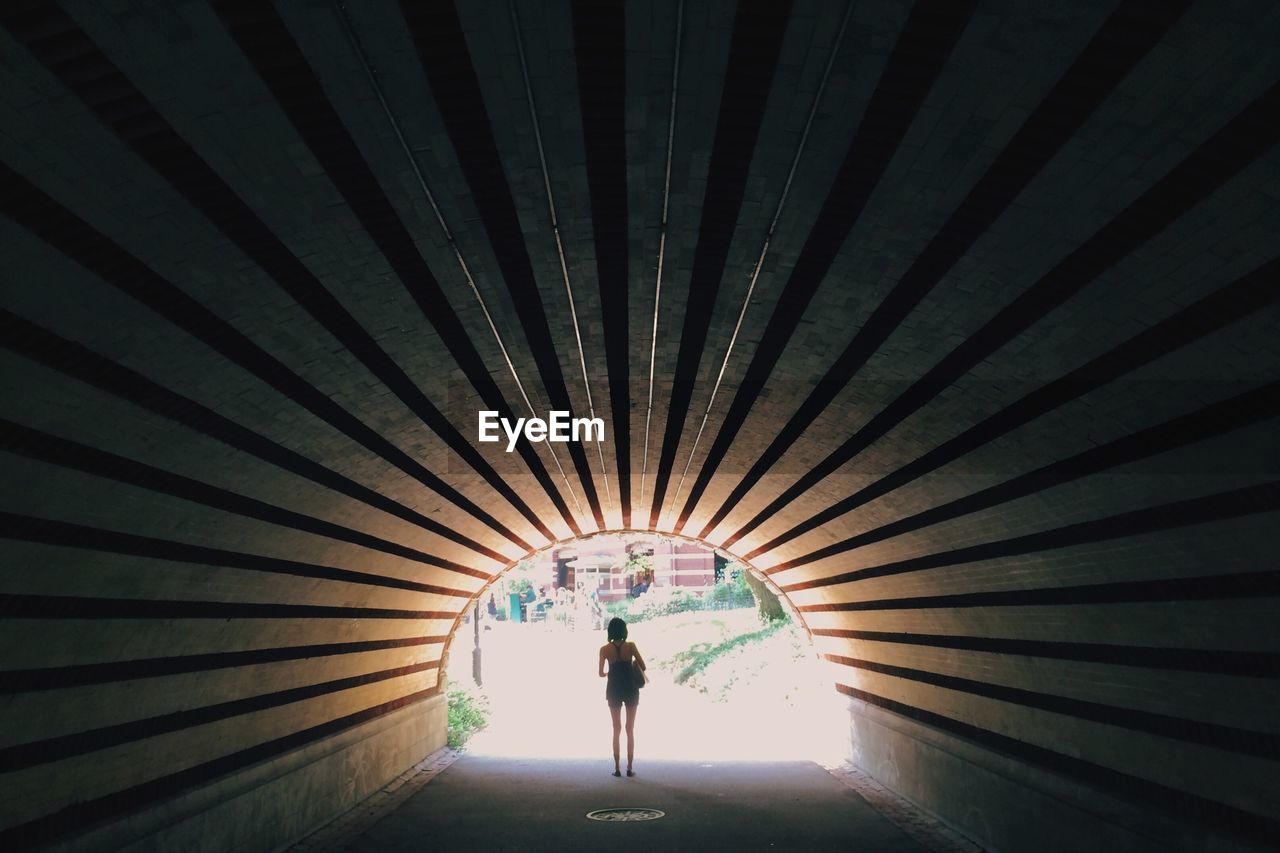 Woman standing at end of tunnel