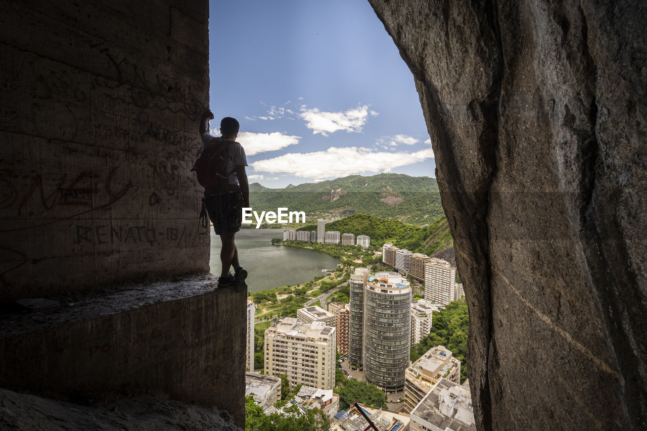 View to rock climbing man on mountain edge with concrete support pilar