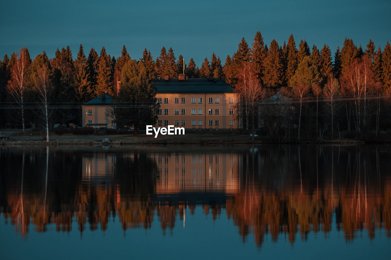 REFLECTION OF TREES ON LAKE AGAINST SKY