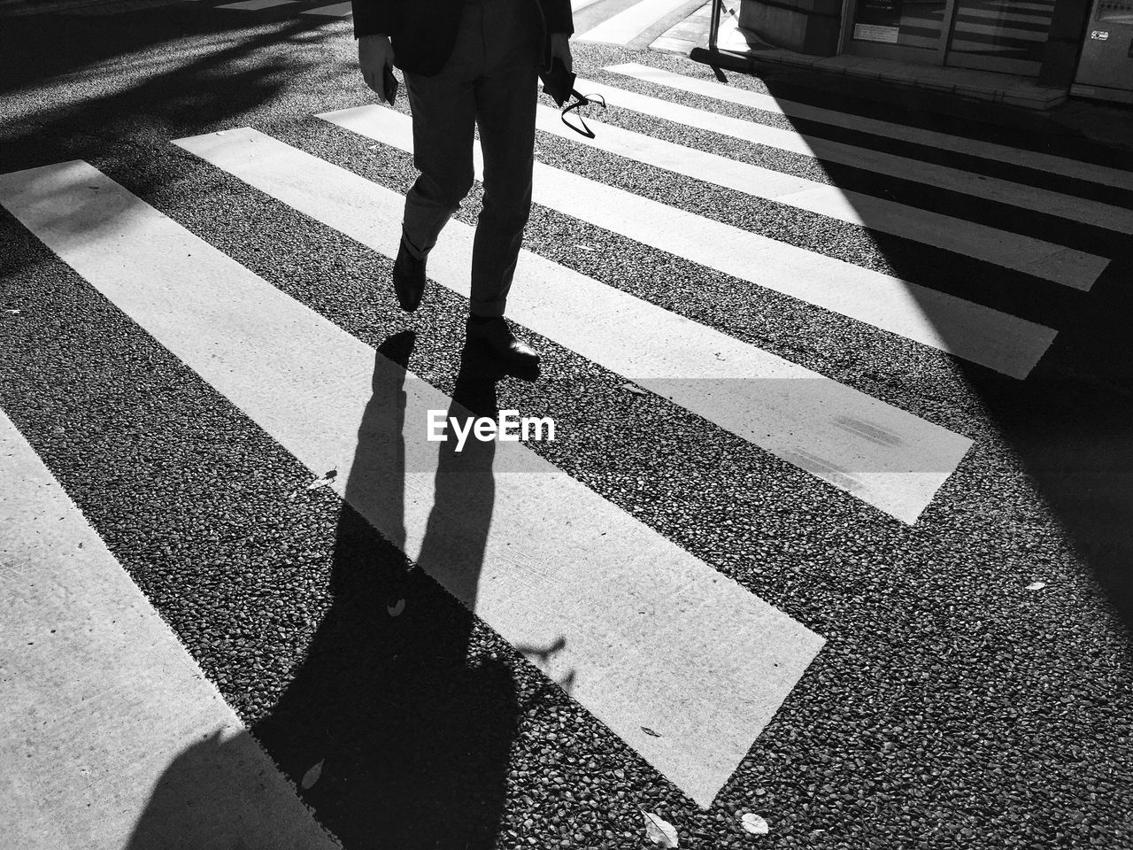 Low section of man walking on zebra crossing