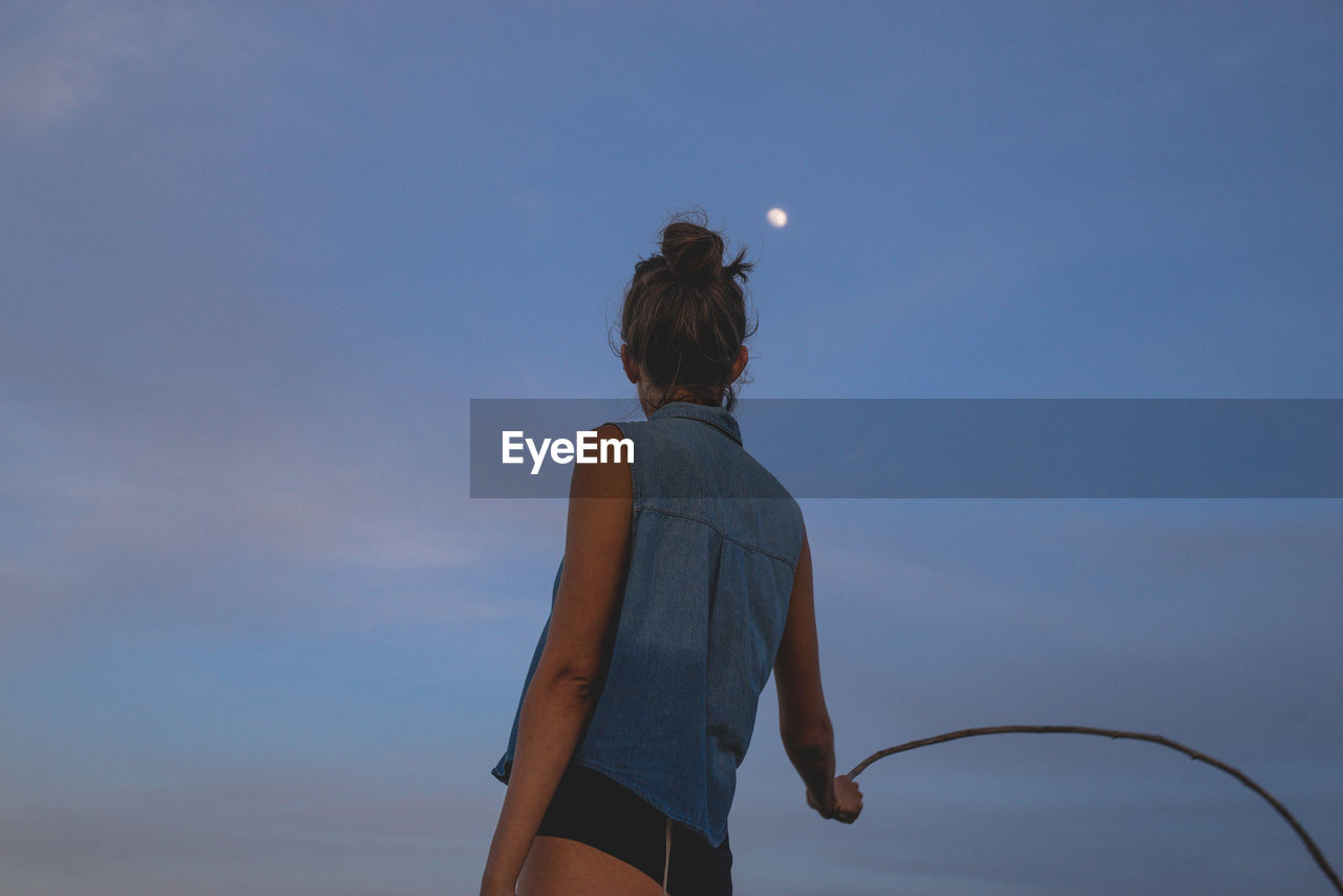 Rear view of woman holding stick at dusk