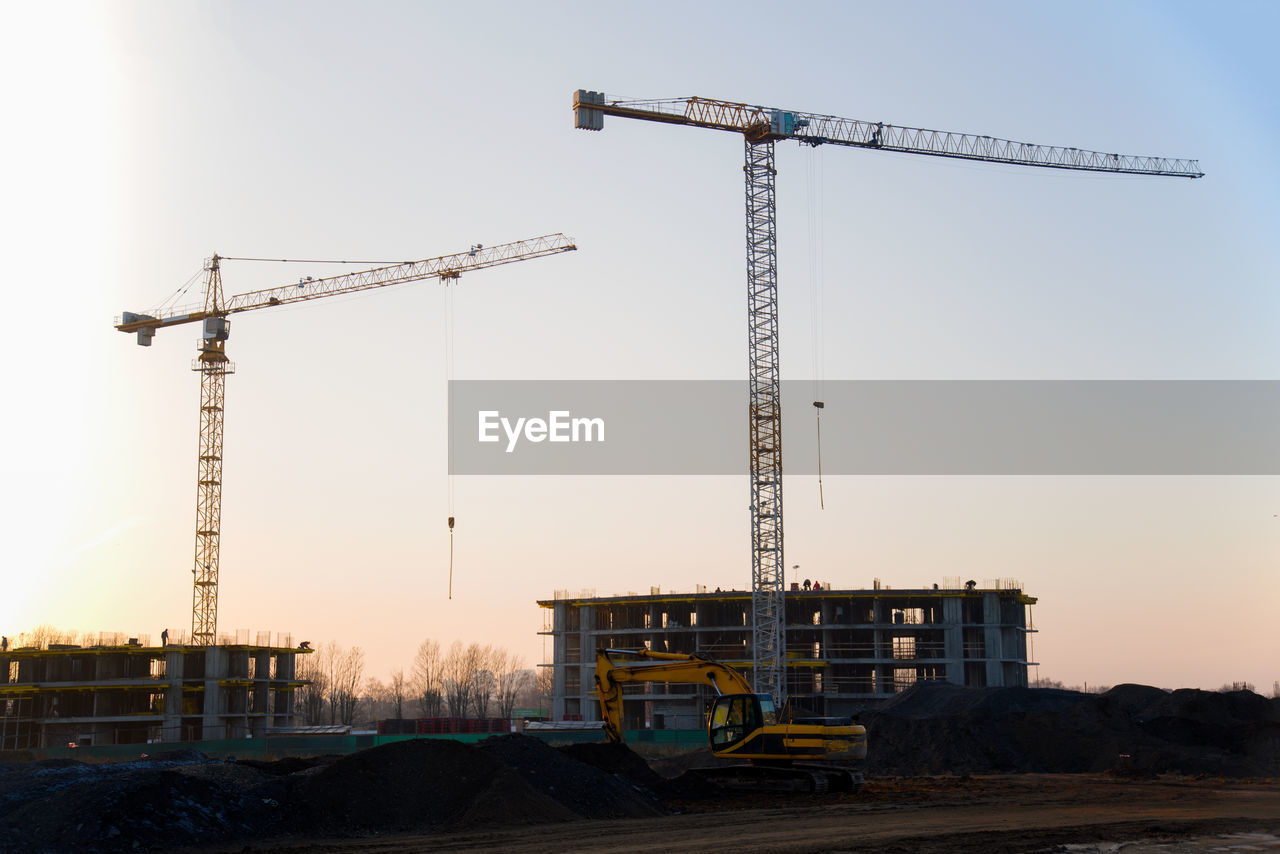 CRANES AT CONSTRUCTION SITE AGAINST SKY