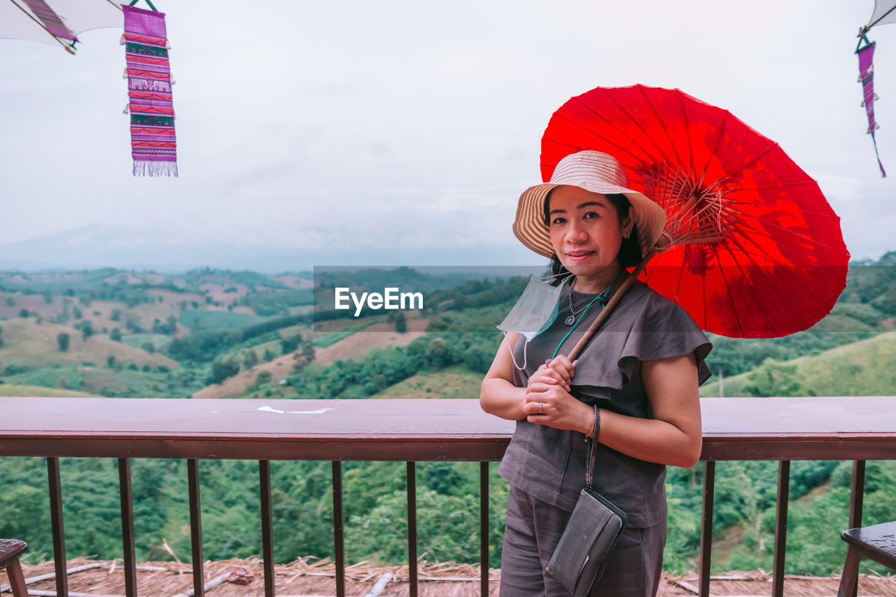 A beautiful asian woman sitting on balcony and looking at mountains and green