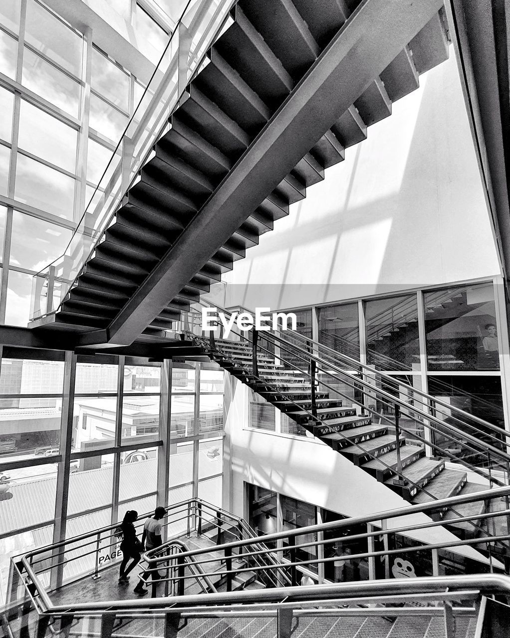 LOW ANGLE VIEW OF PEOPLE ON ESCALATOR IN MODERN BUILDING