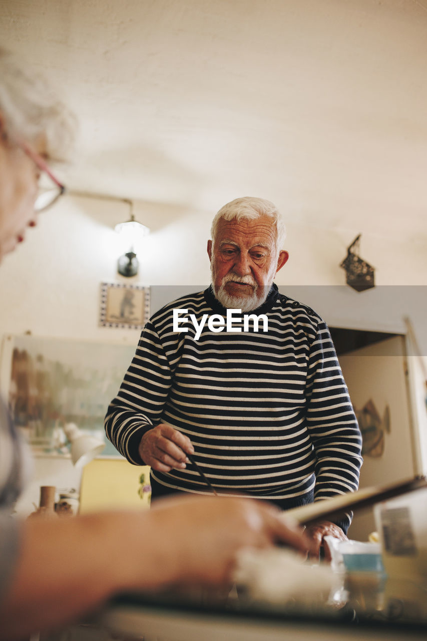 Senior man talking with artist at home