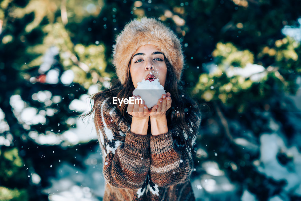 Portrait of woman holding snow standing outdoors