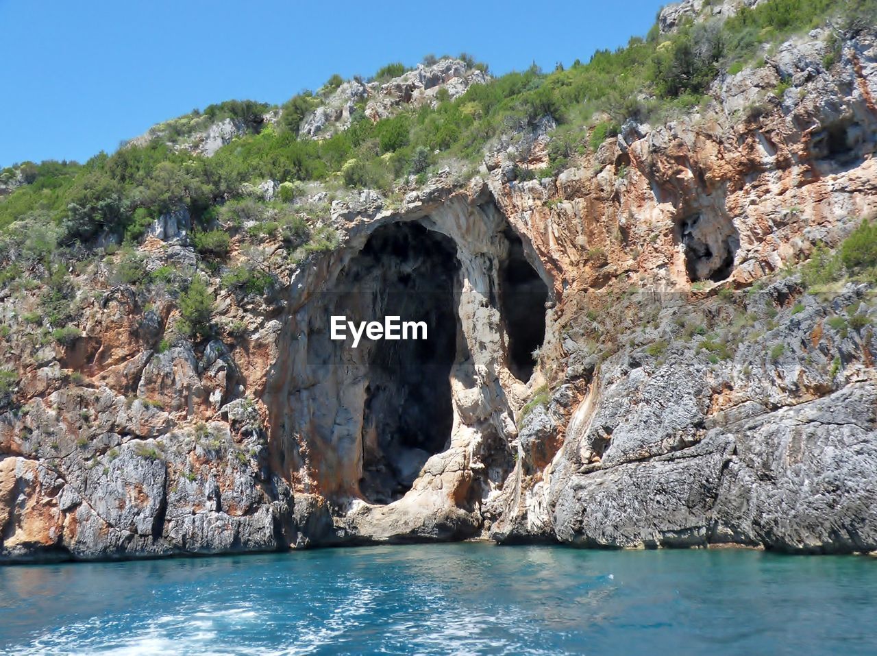 ROCK FORMATIONS ON SEA AGAINST CLEAR SKY