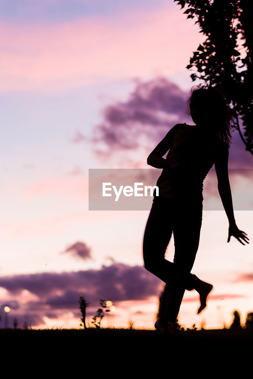 Silhouette woman standing against orange sky