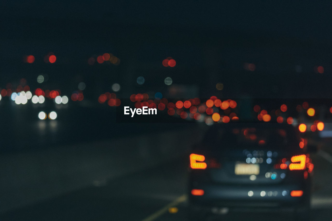 Defocused image of illuminated city against sky at night