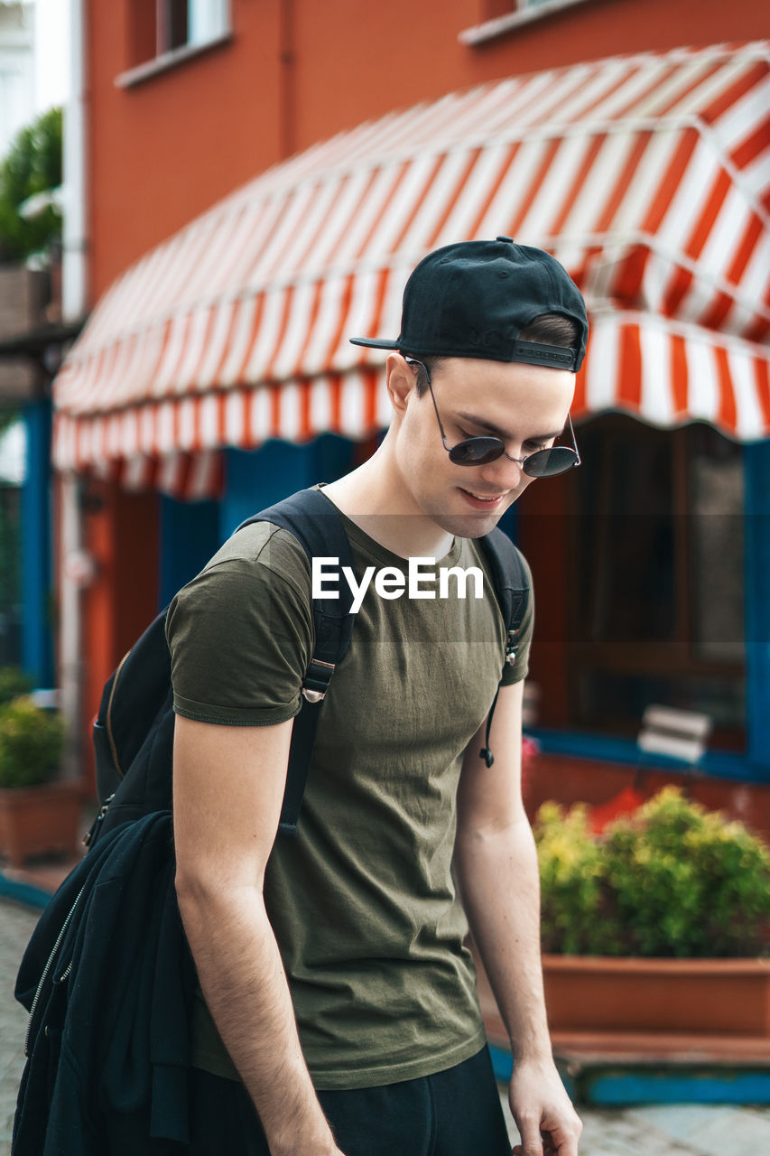 Young man wearing sunglasses standing against built structure