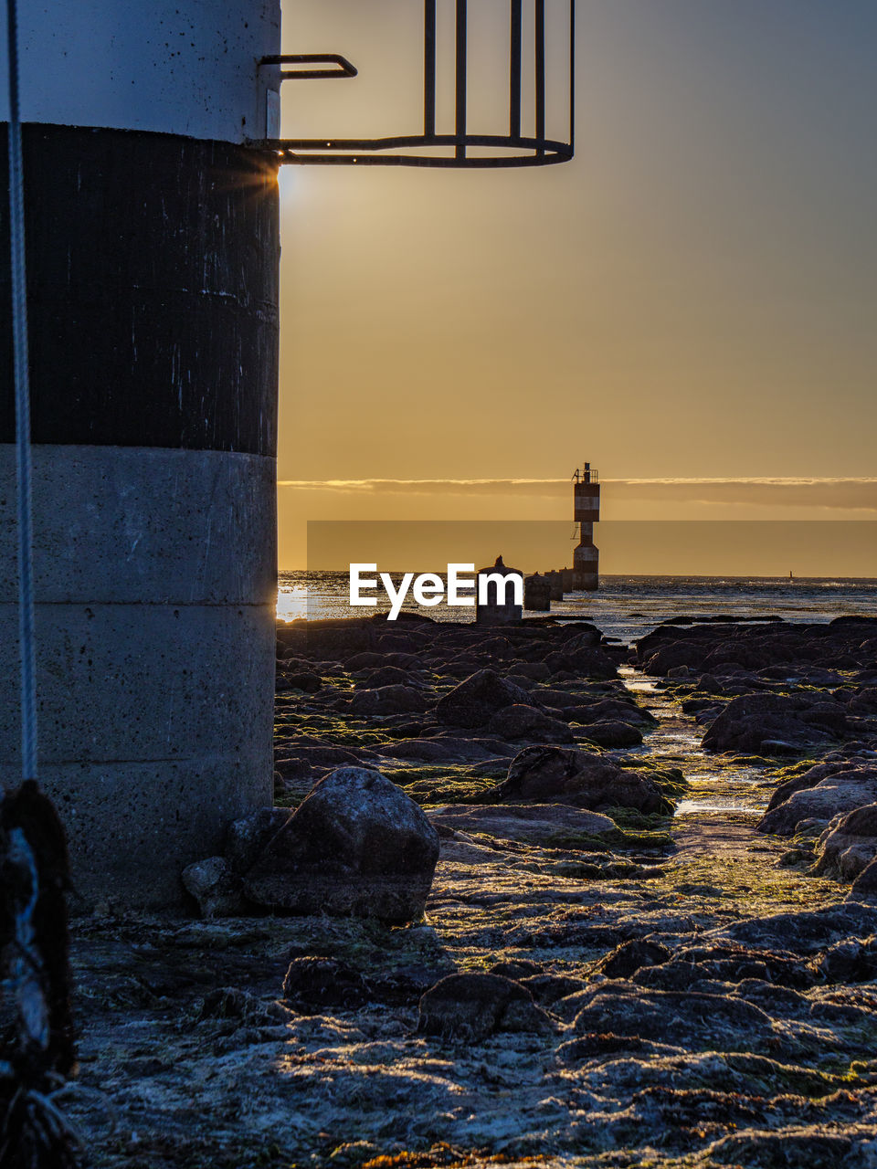ocean, sea, water, reflection, tower, sky, evening, sunset, wave, beach, lighthouse, horizon, nature, architecture, coast, land, dusk, light, shore, built structure, blue, beauty in nature, horizon over water, men, scenics - nature, one person, sunlight, cloud, outdoors, building exterior, silhouette, motion, darkness, sports, standing, tranquility, building, lifestyles