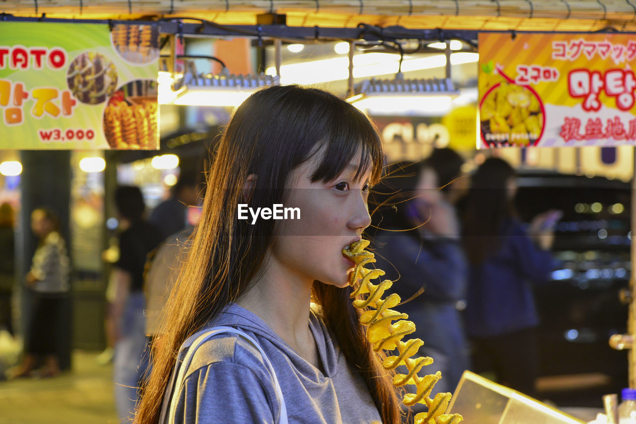 Woman eating street food at market stall