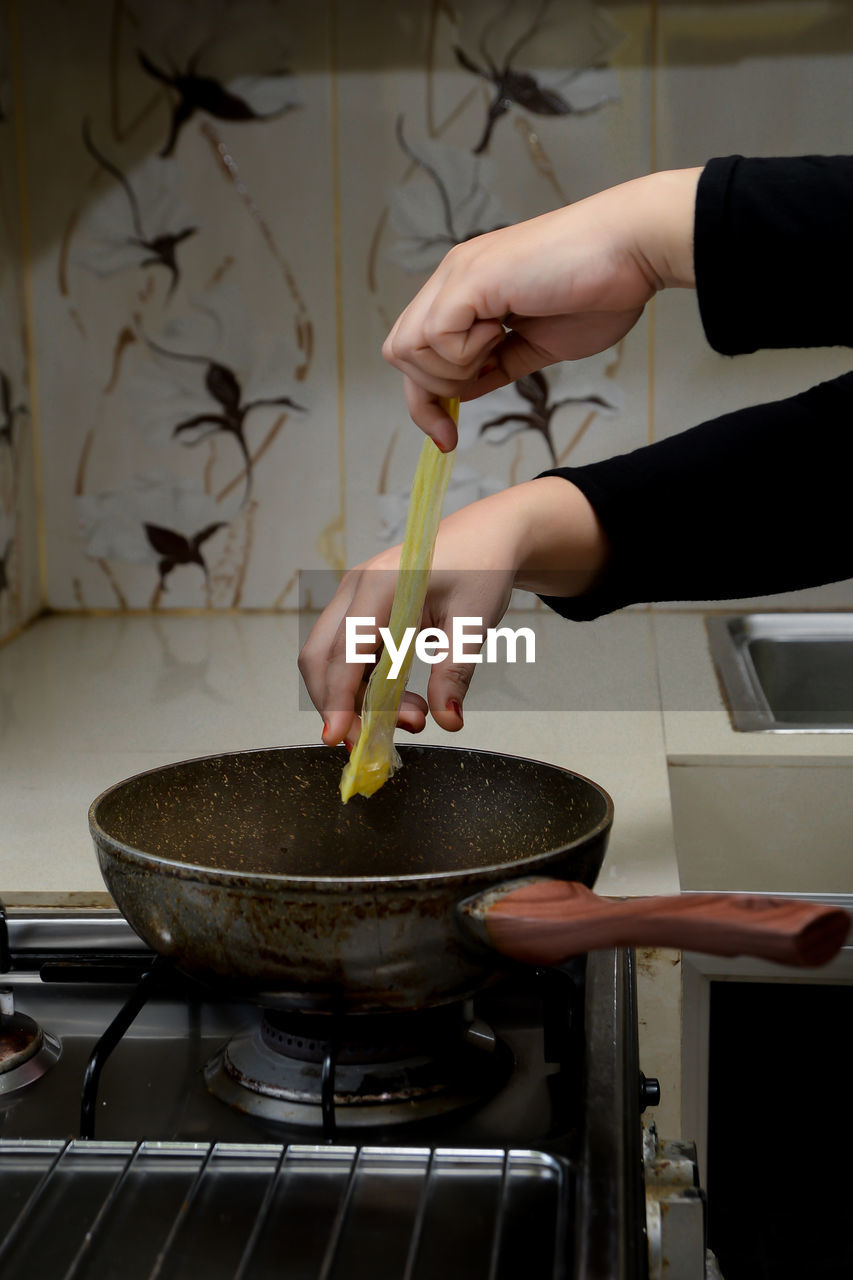 Cropped hand of person preparing food in kitchen