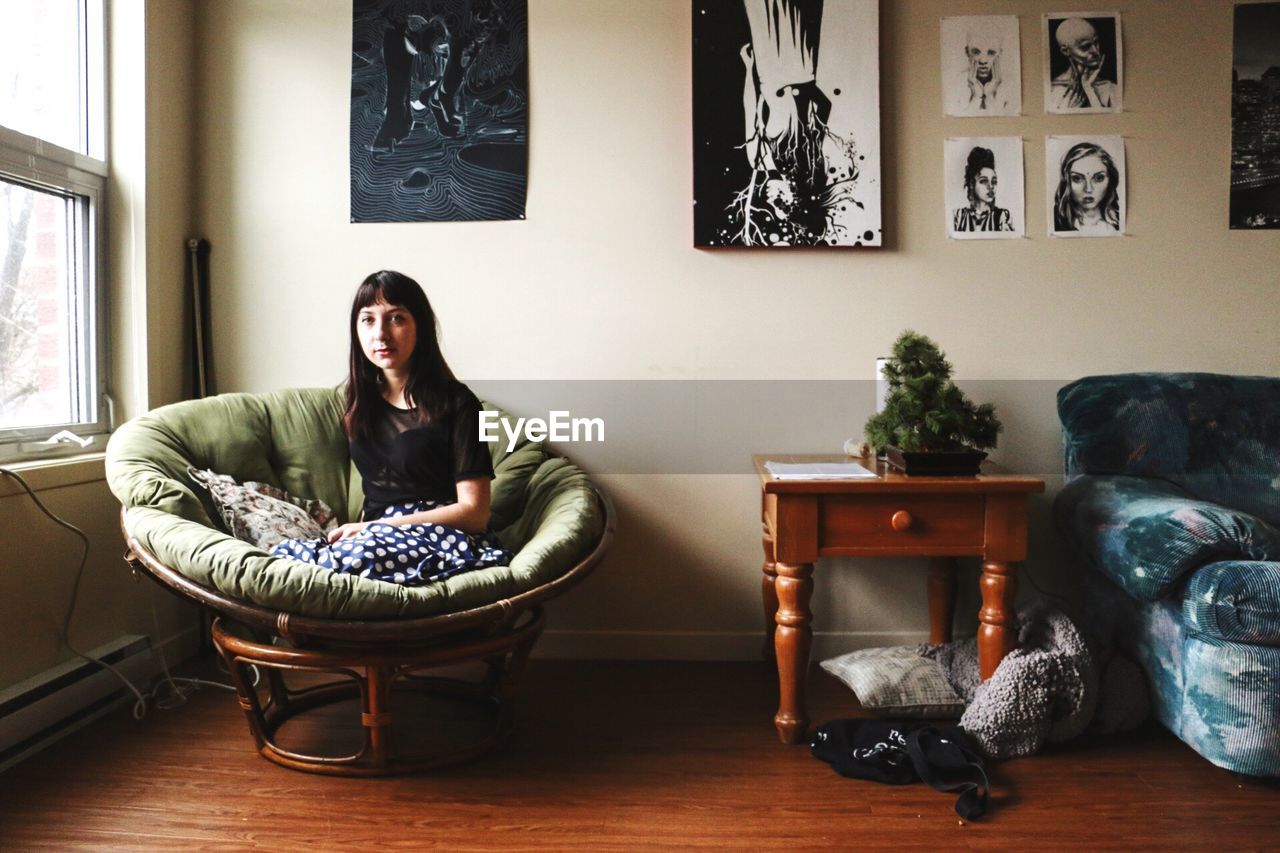 YOUNG WOMAN SITTING ON SOFA AT HOME