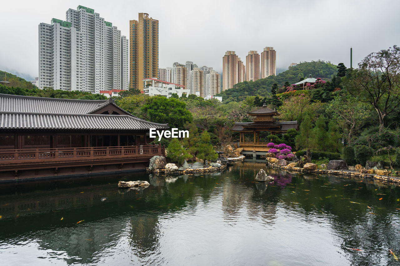 Buildings by river in city against sky