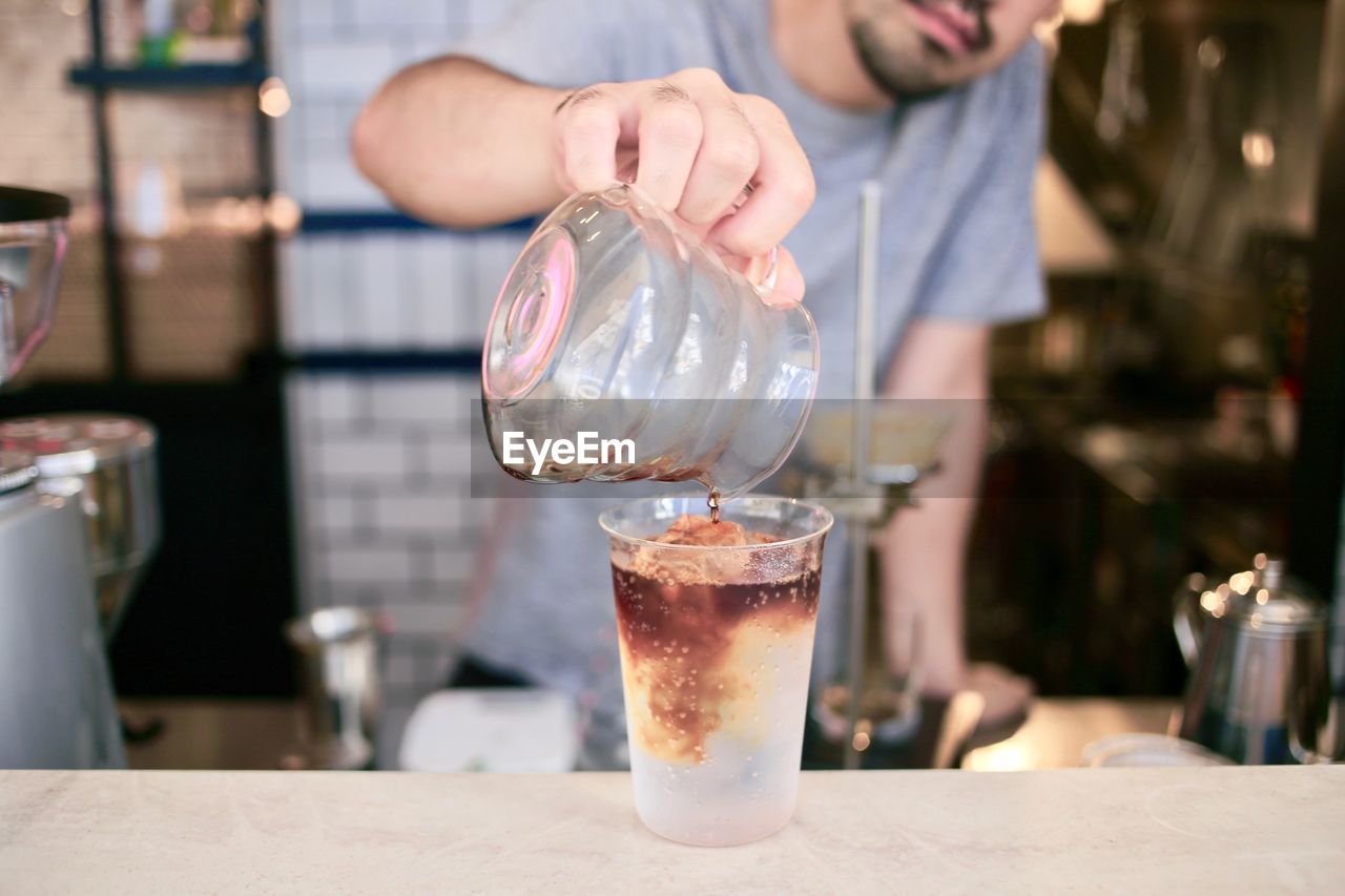 Midsection of male worker making coffee in cafe