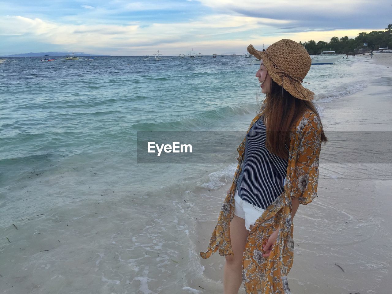 WOMAN STANDING BY SEA AGAINST SKY