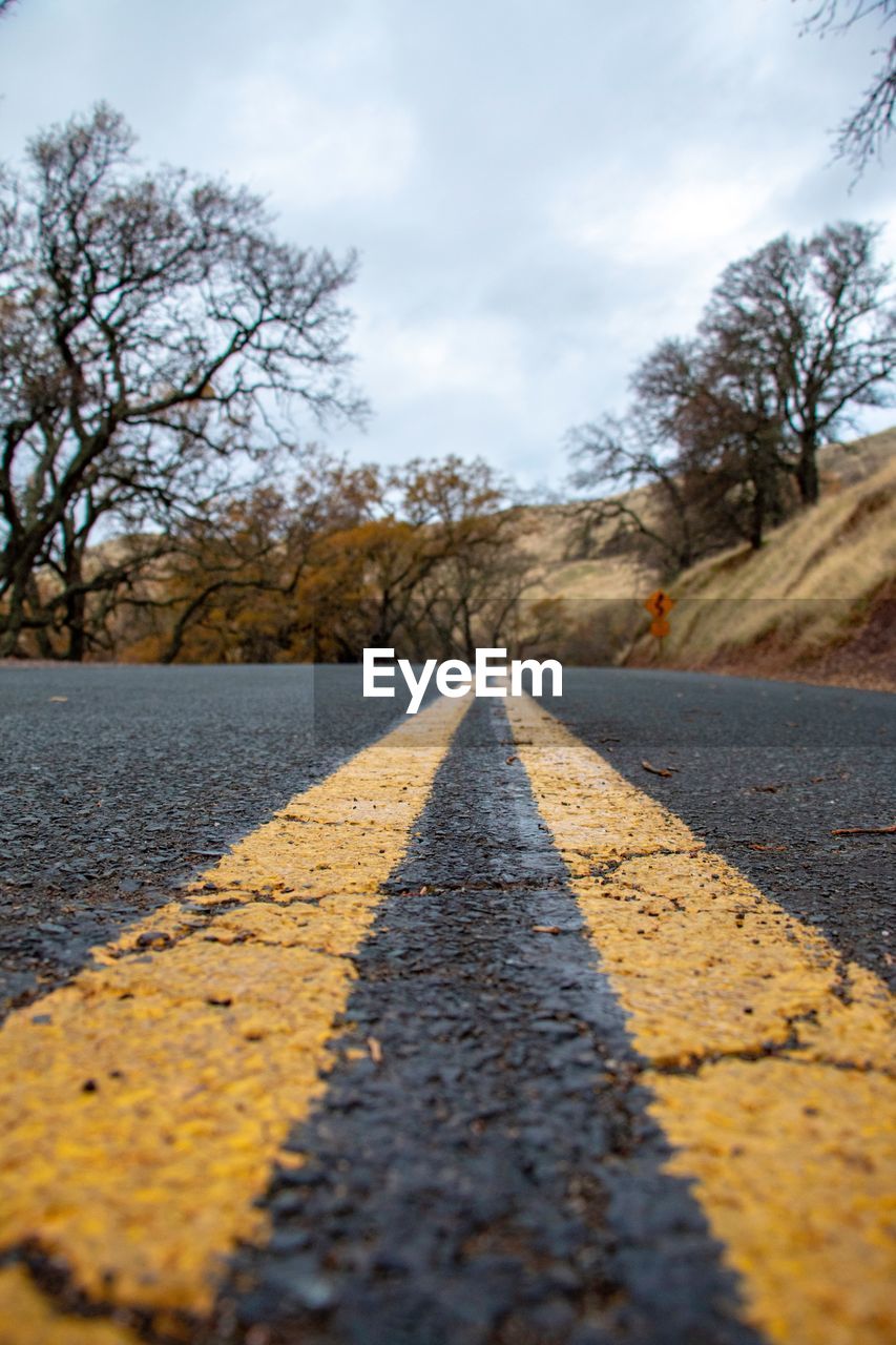 Low angle view down middle of road with trees and hills in background