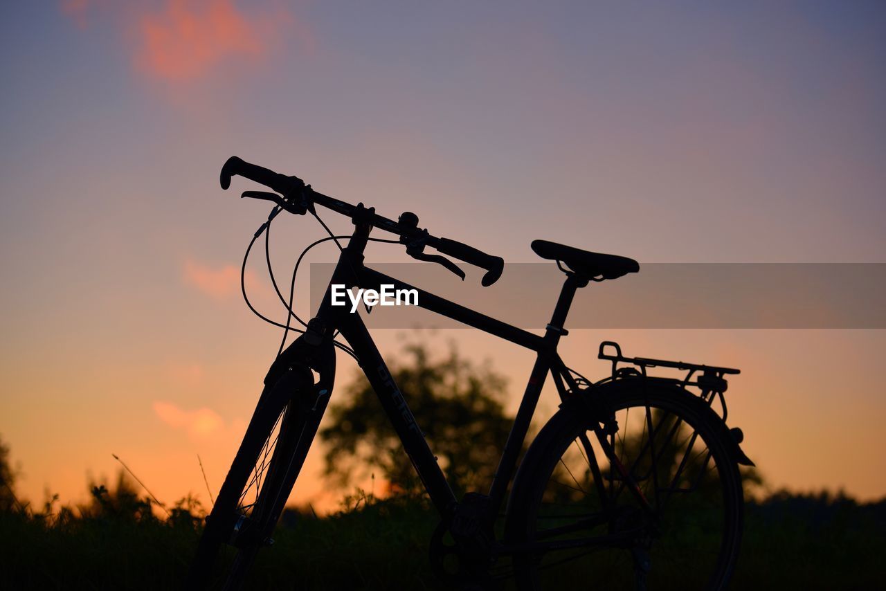 Silhouette of bicycle against orange sky