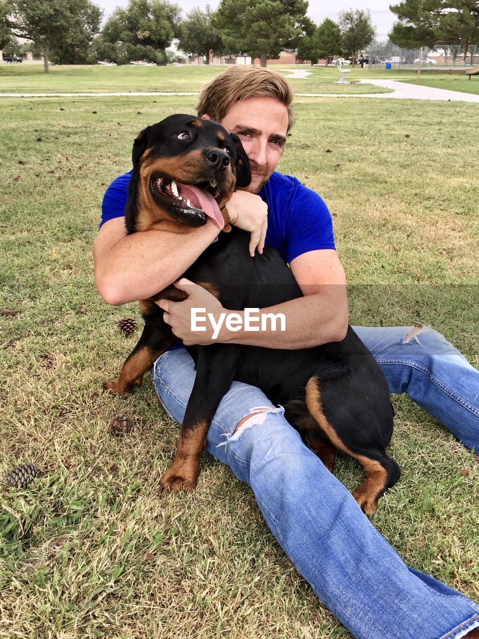 Man with dog sitting on field