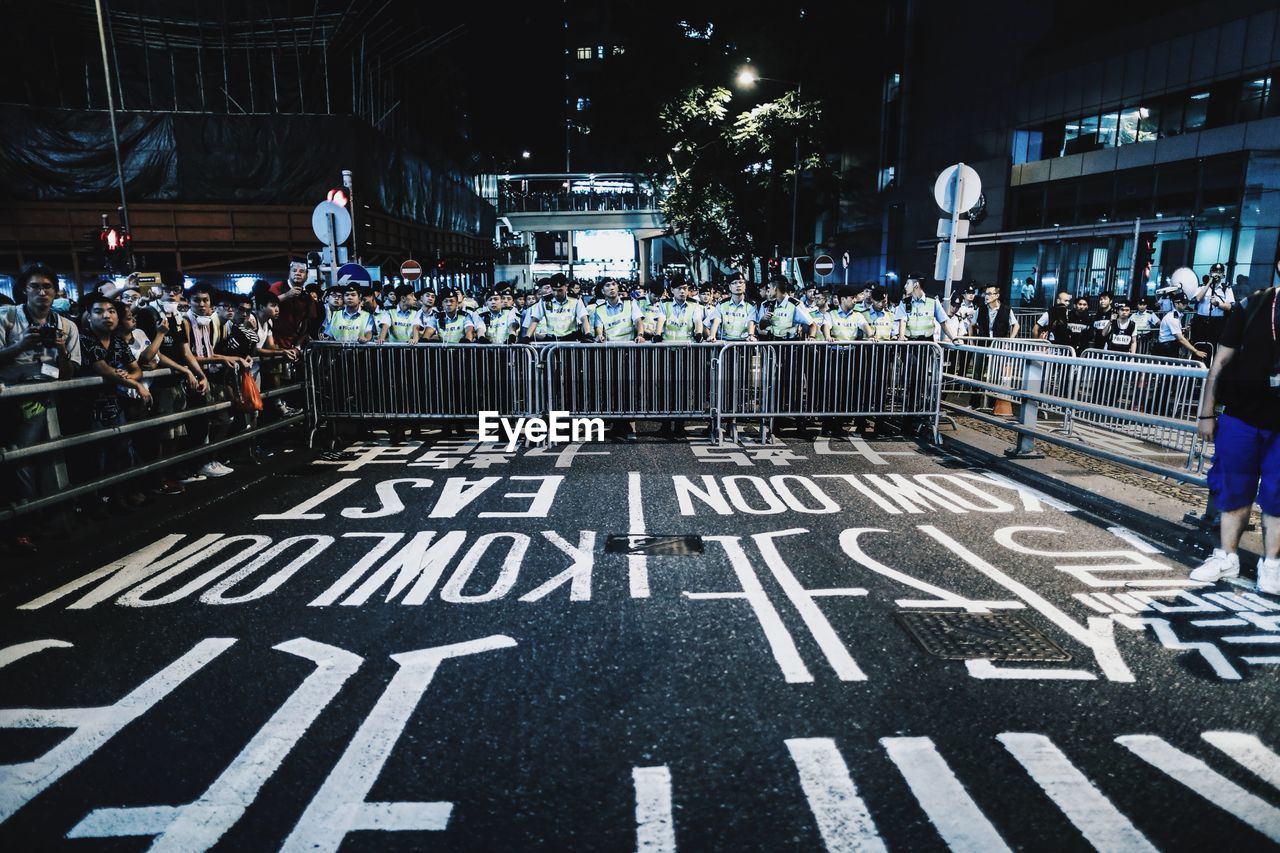 Police officers and people against railings on the street