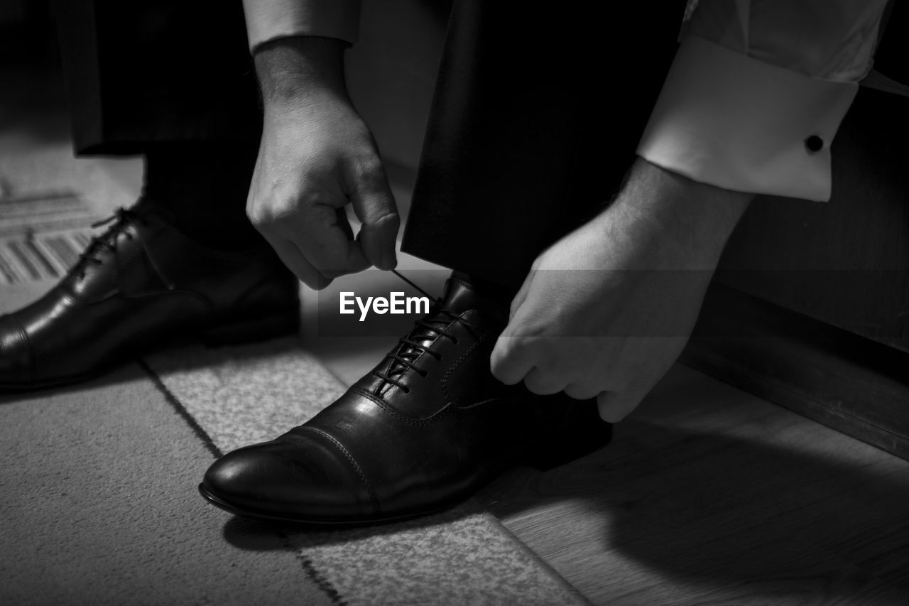 Low section of man tying shoelace at home