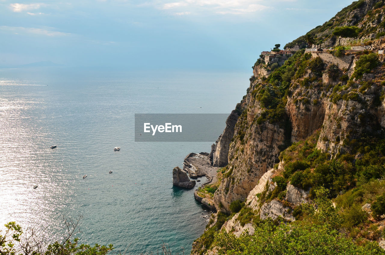 Scenic view of sea by cliff against sky