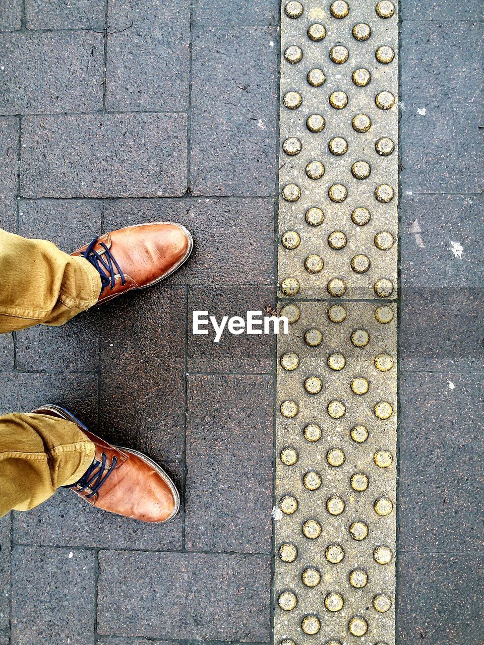 Low section of man standing on paved street