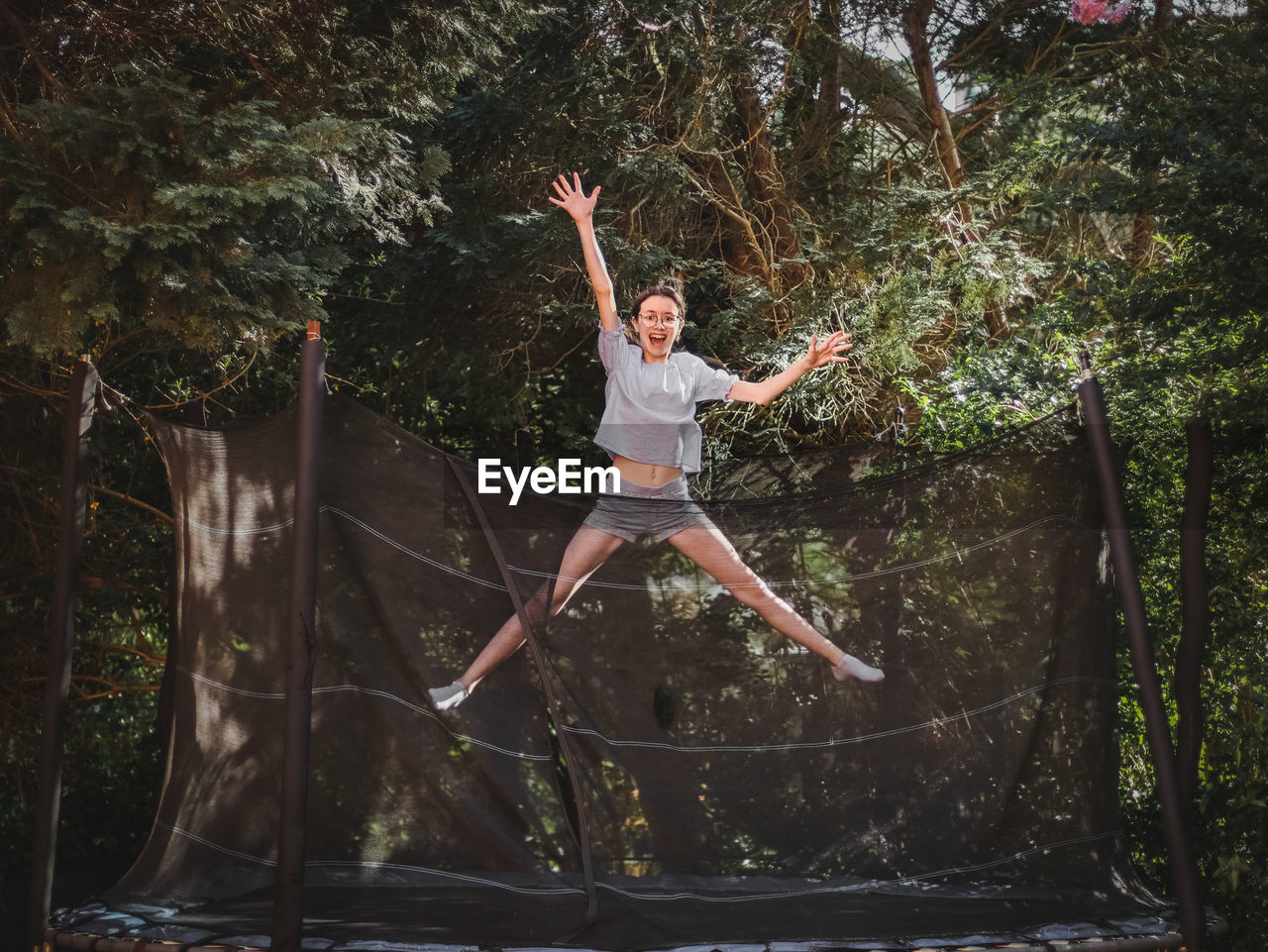 A beautiful slender caucasian teenage girl in shorts and a blouse jumps on a trampoline