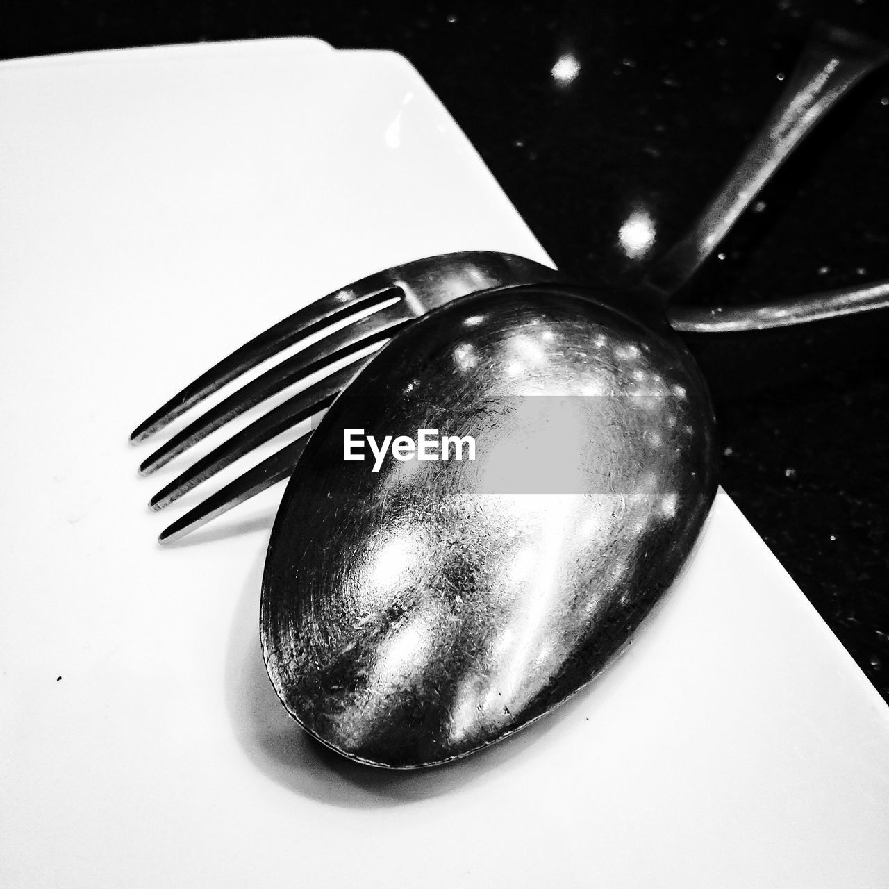 Close-up of plate with fork and spoon crossed upside down