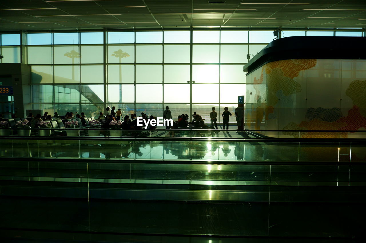 reflection, group of people, large group of people, crowd, travel, indoors, architecture, light, glass, night, airport, transportation, built structure, window, building, men, mode of transportation, silhouette, airport departure area, interior design, adult, city, passenger, women, travel destinations, urban area, lifestyles, public transportation, tourism, airport terminal, transparent, nature, city life, journey, ceiling