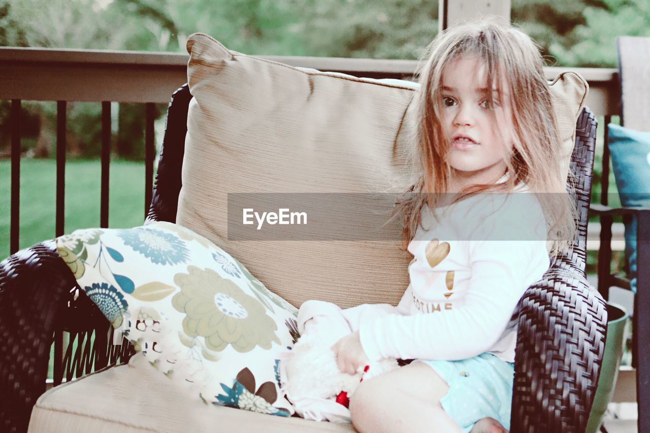 Girl sitting on armchair at porch