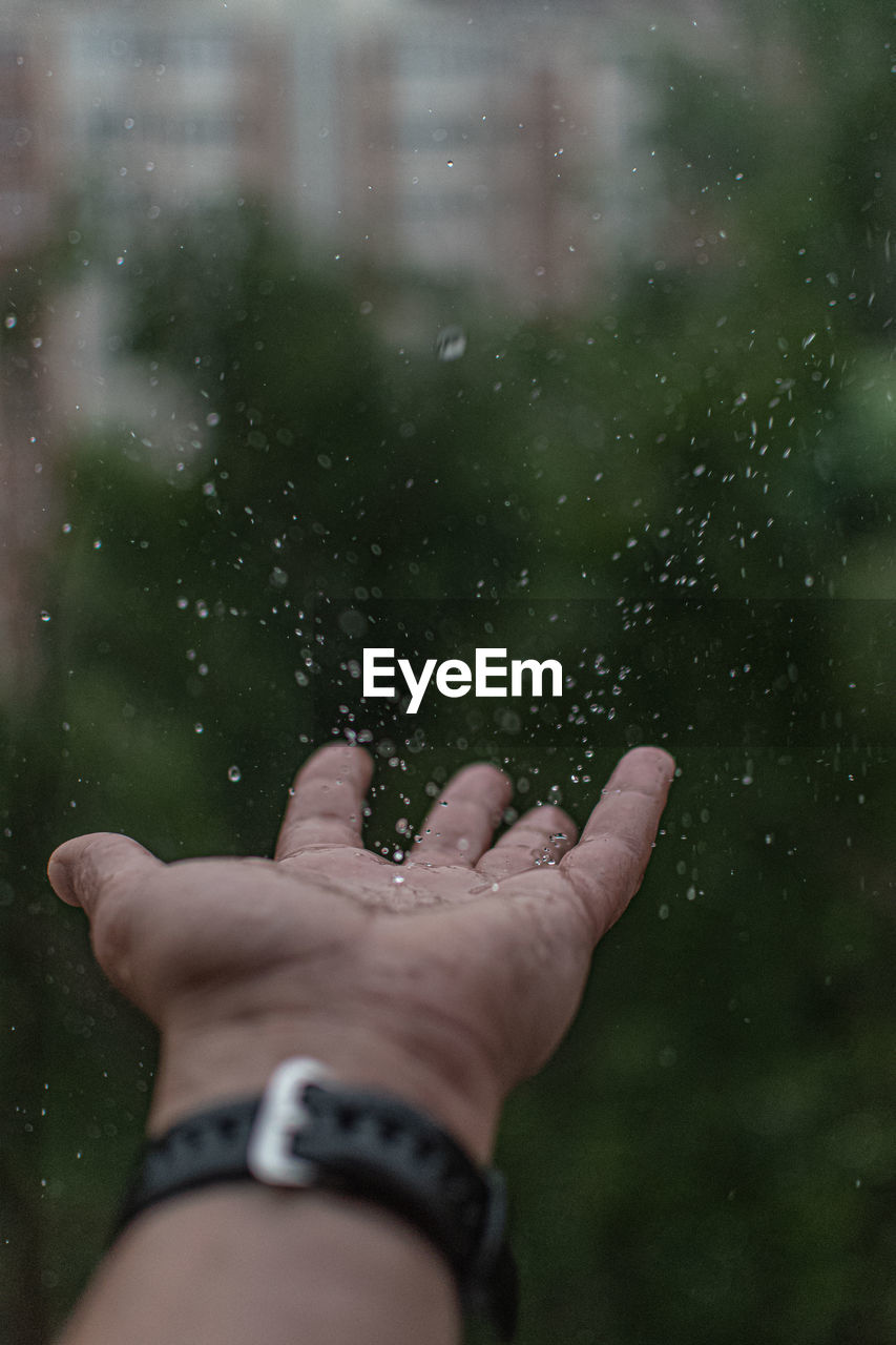 Cropped image of person hand on wet window during rainy season